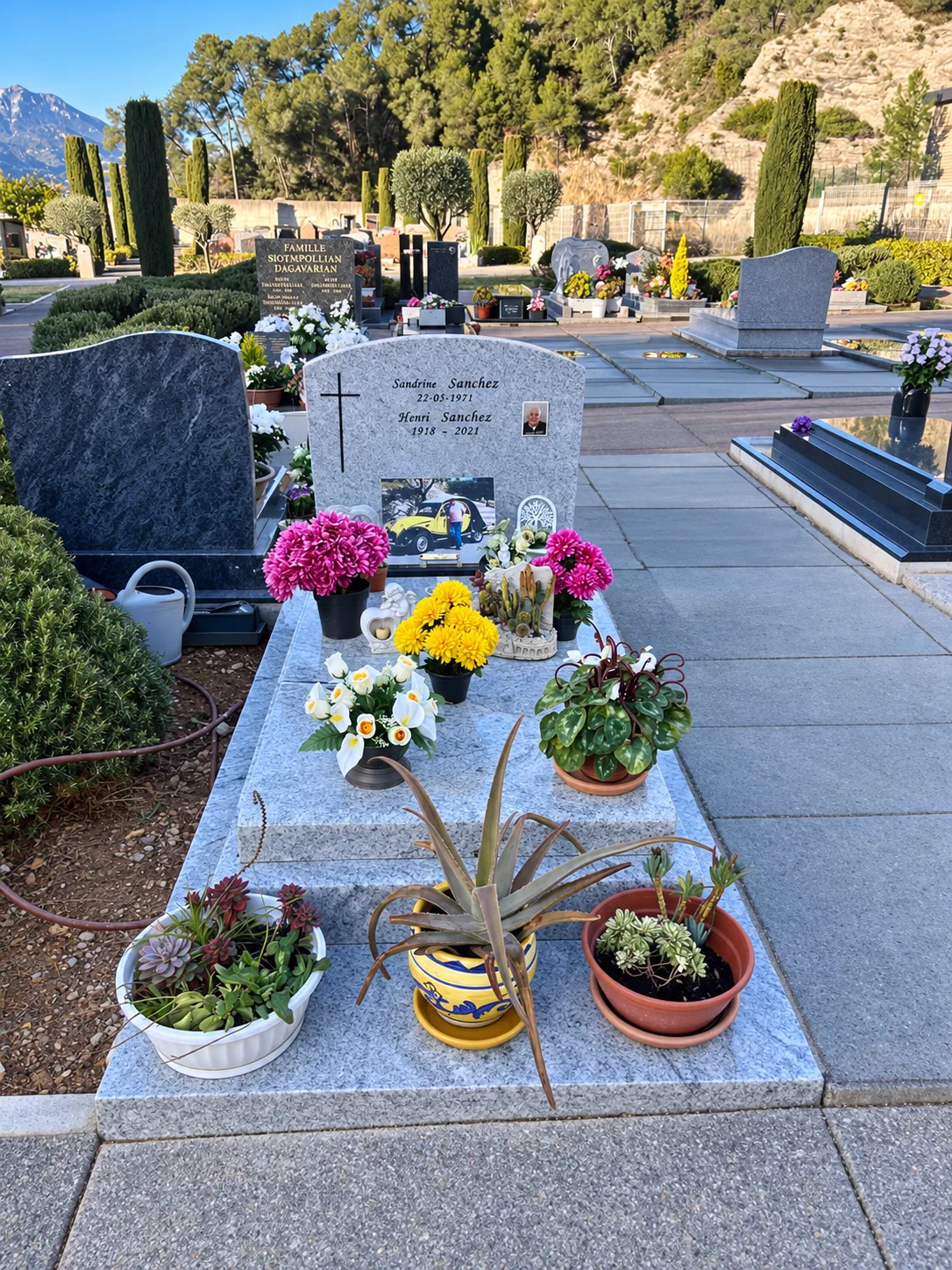 Monument en granit clair fleuri dans un cimetière méditerranéen